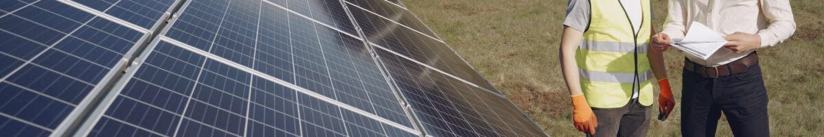 Foreman and businessman at solar energy station. Businessman and worker near solar energy batteries. Business client showing photovoltaic detail to foreman. Two men making deal.
